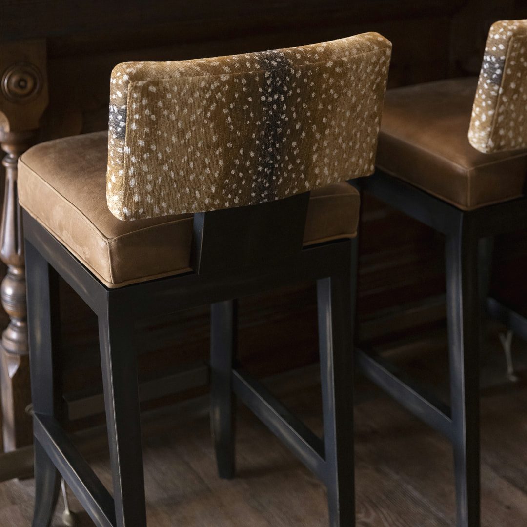 Home bar with animal-print upholstered stools and dark cabinetry
