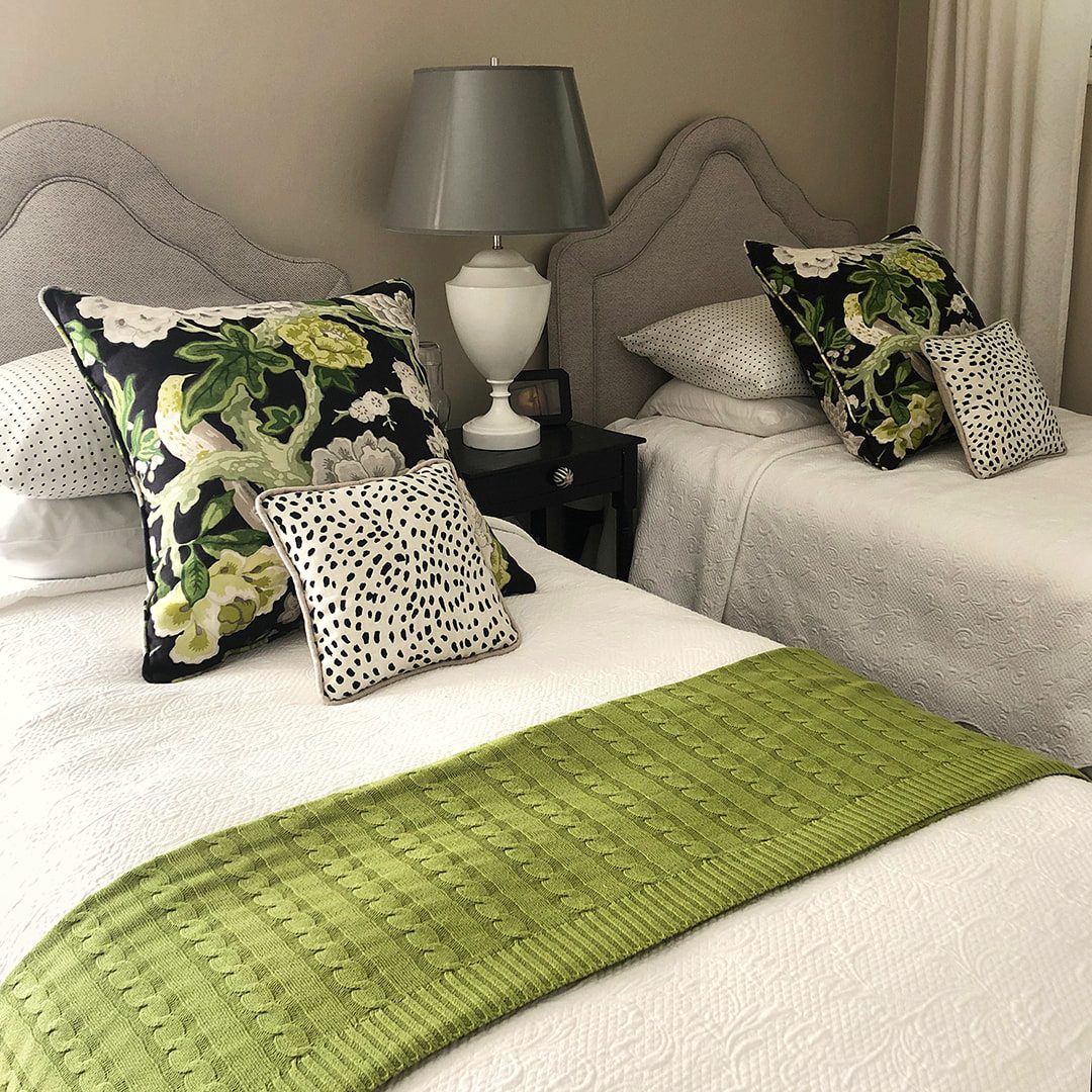 Bedroom with crisp white bedding accented by green pillows and a textured throw
