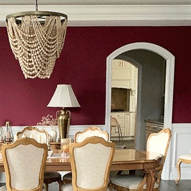 A dining room with a confident deep-red wall color chosen by JK Home Design
