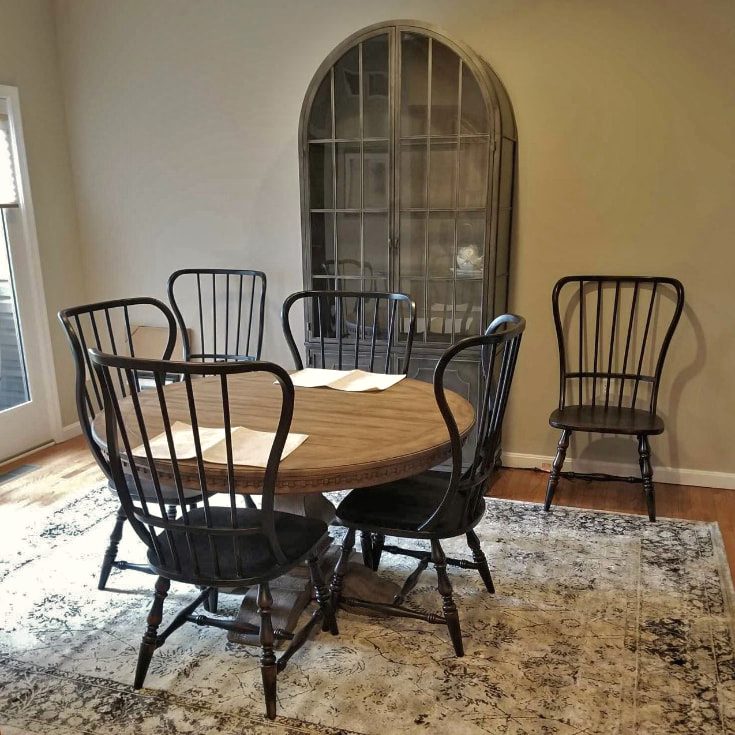 Dining room with a round table, spindle Windsor chairs and an arched display cabinet