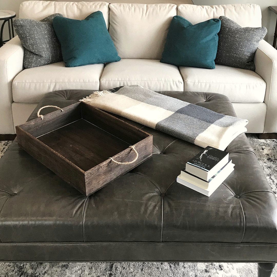 A refreshed living room with a styled ottoman and teal pillows by JK Home Design
