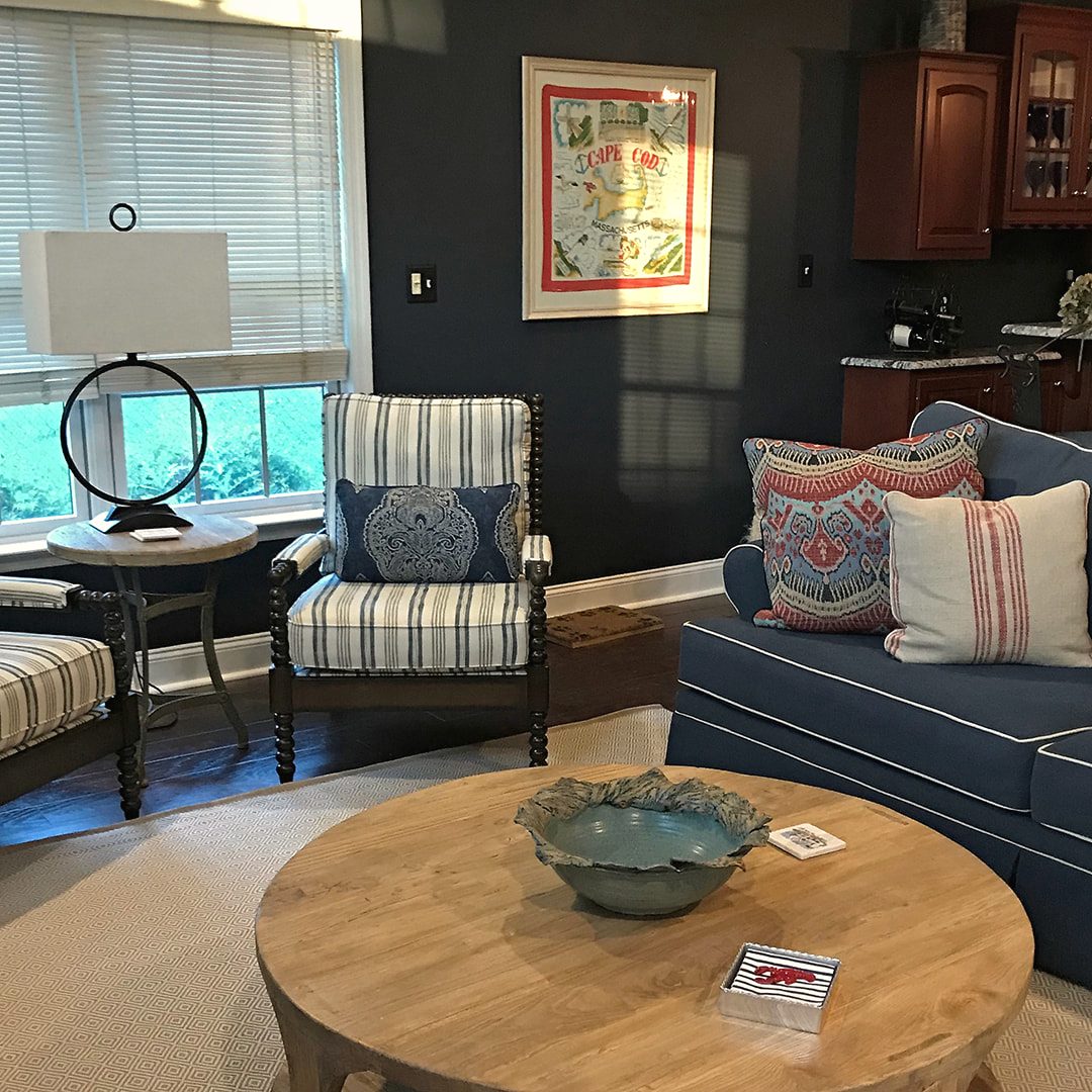 Living room with a round wood coffee table, blue striped armchairs and a layered area rug, designed by JK Home Design