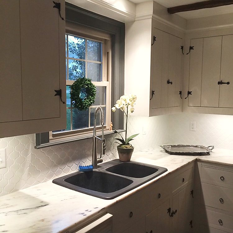 Kitchen with dark lower cabinetry, white upper cabinets and an orchid on the counter