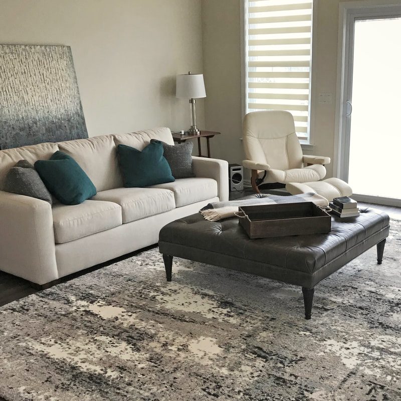 Living room with a large cream sectional, patterned drapery and a dark wood coffee table